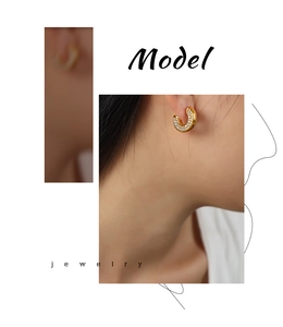 Close-up of gold-plated C-shaped earrings with clear diamonds worn by a model
