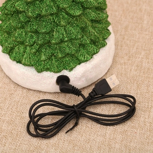 Detail of the USB DC power port on a resin Christmas music box with green glitter texture