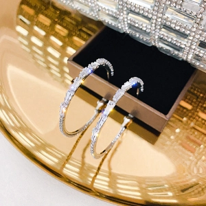 Macro view of silver hoop earrings featuring baguette and round zircon crystal embellishments