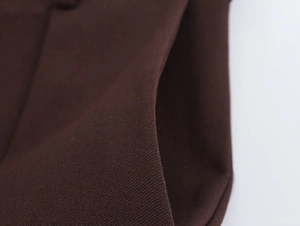 Detail der dunkelbraunen Twill-Stoffstruktur und Nähte an der legeren Anzughose