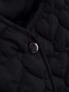 Close-up of black wave quilted jacket fabric with a shiny silver metal button detail