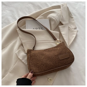 Detail of dark brown woven texture fabric and leather label on retro underarm bag