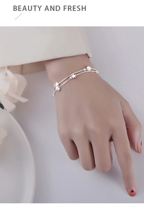 Close-up of double-layer silver star bracelet with beads on female wrist
