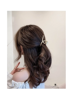 Golden flower hair claw clip with rhinestones and tassels shown in a half-up hairstyle