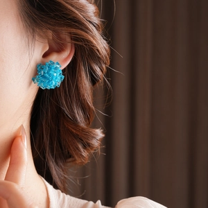 Close-up of vibrant blue glass bead flower cluster earrings worn on a model earlobe