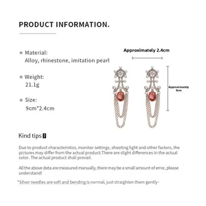 Detailed view of elegant fringe earrings with red oval stones and faux pearl accents