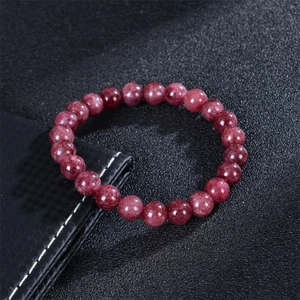 Natural strawberry quartz beaded bracelet with round dark red gemstones on black texture