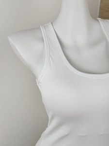 Close-up of white ribbed fabric texture and neckline detail on a slim-fit sports tank top