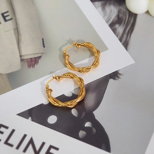 Detailed view of gold twisted rope hoop earrings resting on minimalist fashion magazine