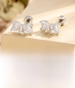 Macro view of silver bow stud earring with heart zircon and screw back detailing