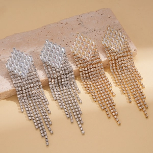 Macro shot of long fringe tassel earrings with zircon rhombic studs on stone