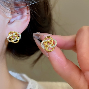 Détail de boucles d'oreilles fleur dorées avec zircon blanc sur l'oreille du modèle