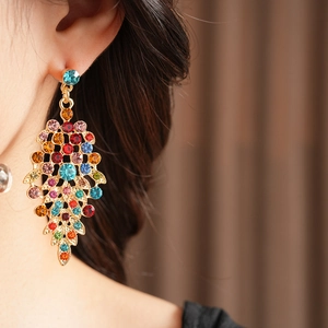 Detail of vintage gold leaf earrings with colorful rhinestones on a female model