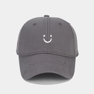 Close-up of deep gray twill cotton baseball cap with white embroidered smiley face design