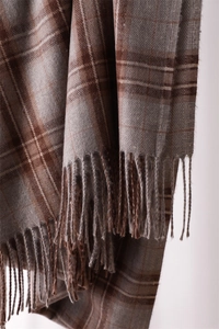 Close-up of brown plaid scarf texture with tassel detail and soft wool-like fabric weave