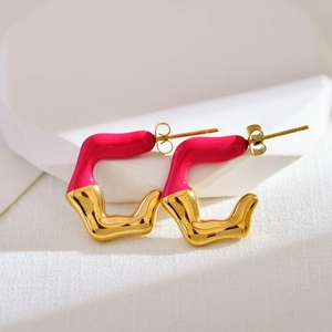 Detail of irregular C-shaped earrings with gold plating and magenta enamel finish