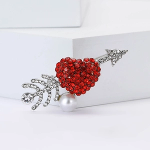 Sparkling rhinestone heart and arrow brooch with a white pearl on a clean studio display