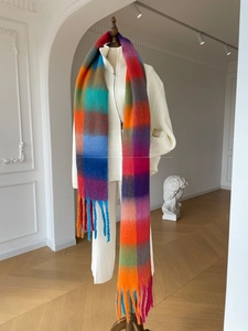 Close-up of thick gradient plaid scarf with colorful chunky tassels and soft wool texture