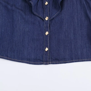 Gros plan sur le tissu denim bleu foncé avec surpiqûres et boutons métalliques dorés