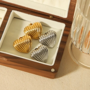 Elegant 18k gold and silver heart-shaped stud earrings with shell texture in a wooden box