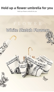 Detail of white umbrella with black tulip sketches and elegant gold J-shaped metal handle