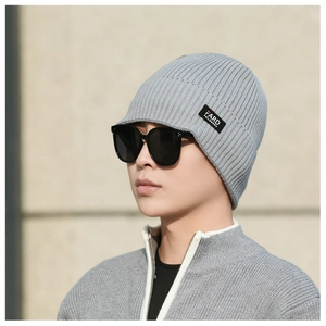 Close-up of grey knitted beanie with ribbed texture and minimalist brand woven label