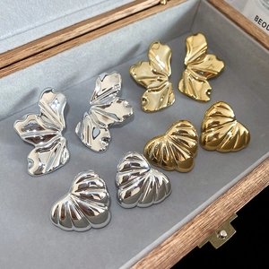 Detailed macro view of irregular metallic butterfly and shell studs in a velvet box