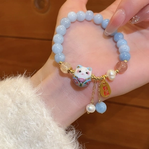 Close-up of pearl and aquamarine beaded bracelet featuring ceramic fortune cat charm