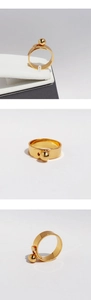 Macro detail of gold ball buckle geometric ring featuring a wide band and metallic finish