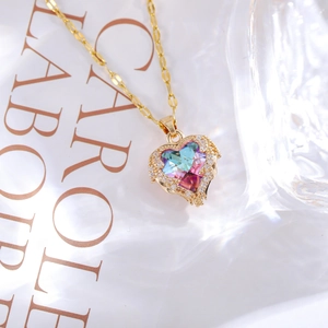 Macro detail of heart-shaped blue crystal pendant with micro-pave diamond halo in gold