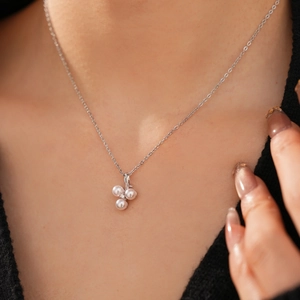Detail of silver pearl cluster necklace featuring three pearls and a small central zircon