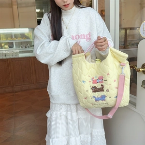 Detail of yellow quilted tote bag with cat embroidery and Luck slogan in a cafe setting