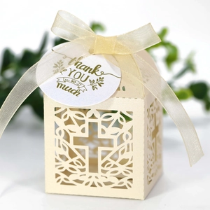 Detail van lasergesneden kruispatroon op beige geschenkdoos met zijden lint en bedankkaartje