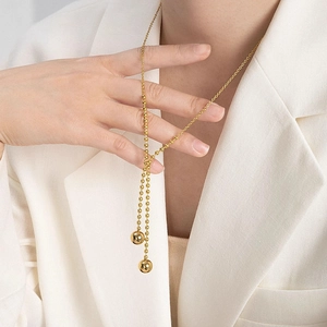 Elegant gold-plated Y-shaped beaded necklace with dual ball pendants on a model