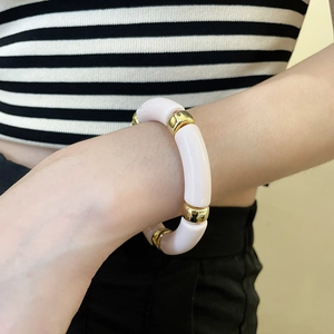 Detailed shot of pink acrylic geometric tube bracelet with gold metal spacer rings