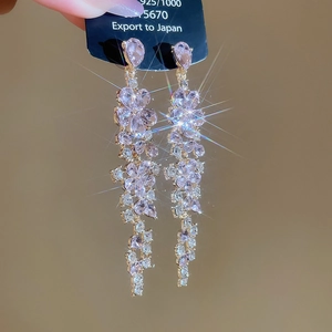 Detailed macro view of pink crystal flower tassel earrings on a golden metal base