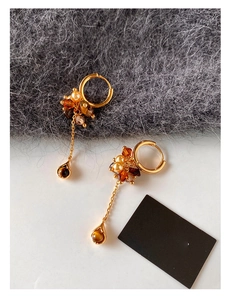 Detail of vintage gold earrings featuring tiger eye stone pendants and pearl tassels