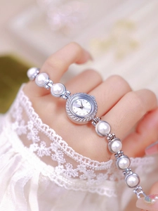Detail of silver pearl bracelet watch with crystal bezel worn on a model's wrist