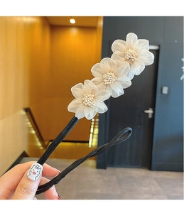 Detail view of a floral hair braider with three cream gauze flowers and pearl centers