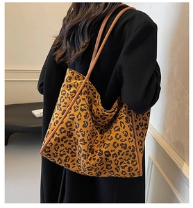 Detail view of large leopard print tote bag with brown leather trim on a model