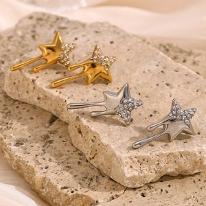 Detail of liquid metal star earrings with crystal inlay on stone and satin background