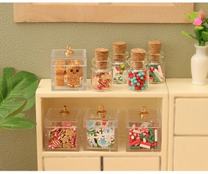 Macro detail of miniature gingerbread cookies and colorful candies in tiny glass jars