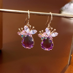 Vue macro de boucles d'oreilles dorées avec pierres violettes et zircons multicolores