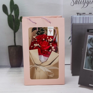 Detail of red soap rose bouquet in pink window gift bag with carnations and card