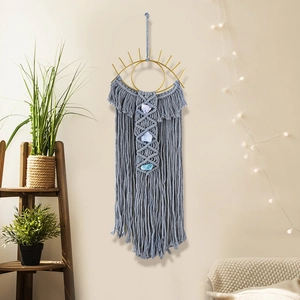 Detail of grey handmade macrame wall hanging with golden metal eye and natural crystals