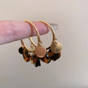 Detail view of large gold hoop earrings with brown leopard print acrylic charms