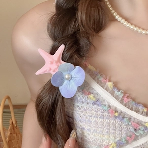 Detail view of starfish hair clip with fabric flower and pearl on hair side
