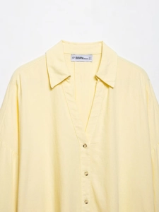 Detail view of light yellow linen shirt fabric texture and neat button-down stitching
