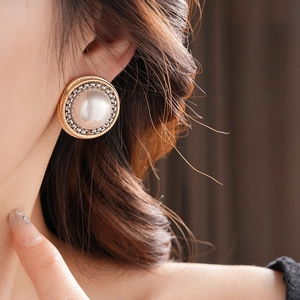 Gros plan d'une boucle d'oreille vintage dorée avec perle portée par un mannequin