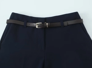 Détail du pantalon bleu foncé avec une ceinture marron et une boucle argentée